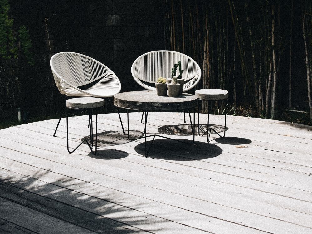 2 chairs and a wooden table places on circular outdoor decking