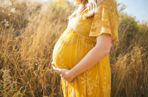 Women cradling her pregnancy bump in a yellow dress